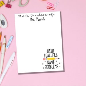 May include: White notepad with the text "From the desk of: Mrs. Parrish" at the top. The bottom of the notepad has the text "MATH TEACHERS HAVE PROBLEMS" with a yellow pencil drawn horizontally through the text. The pencil has a pink eraser.