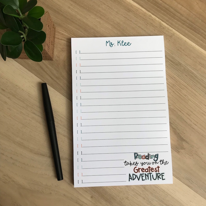 Pu&ograve; includere: Blocco note bianco con linee nere e un bordo turchese. Il blocco note ha il testo "Ms. Klee" in alto e il testo "Reading takes you on the Greatest ADVENTURE" in basso.