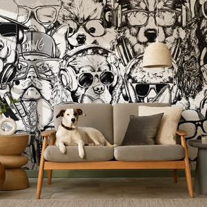 May include: A dog rests on a gray sofa in front of a black and white dog-themed wallpaper. The wallpaper features dogs wearing sunglasses and headphones. A small side table and a hanging lamp are also visible.