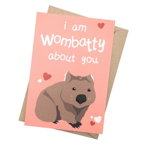 May include: A pink card with a cartoon wombat and the text "i am wombatty about you". There are several small red and white hearts on the card.