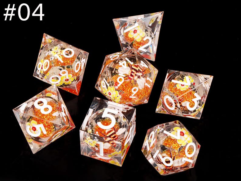 May include: Set of seven clear dice with orange and yellow glitter and floral designs. The dice are numbered 1 through 6 and have a bee design on the 6 side.