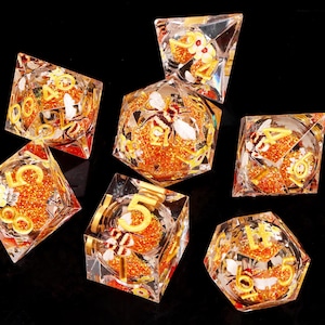May include: Set of seven clear dice with gold numbers and glitter. Each die features a bee and flower design.
