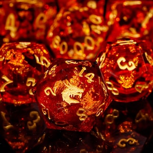 May include: A set of red and gold dice with a dragon design. The dice are made of glass and have a sparkly finish.