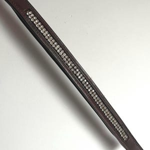 May include: A brown leather browband with two rows of clear rhinestones.