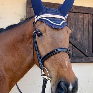 thoroughbred horse wearing navy soundproof, noise cancelling,acoustic ear bonnet