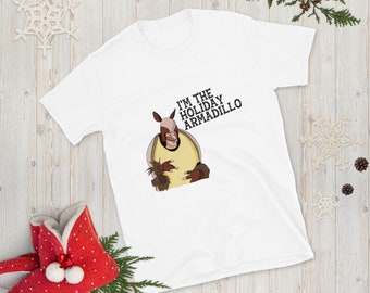 May include: White t-shirt with a cartoon armadillo wearing a yellow shirt and the text "I'm the Holiday Armadillo".