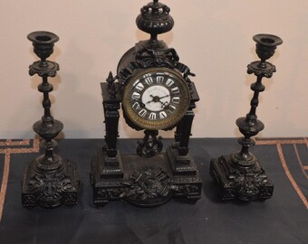 An Antique French Embossed and Ebonised Metal Cased Clock and Garnitures