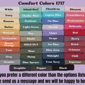 May include: A color chart displays a variety of Comfort Colors 1717 fabric swatches. Colors include white, ivory, and black, with text indicating each shade. The image includes a message about custom color options.