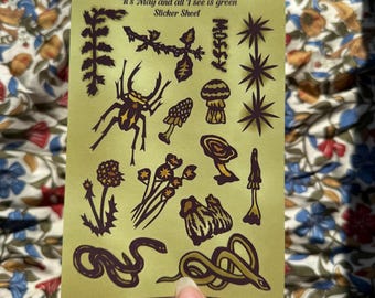 May include: A light green sticker sheet featuring dark brown and gold illustrations of a beetle, various mushrooms, wildflowers, and two snakes. The text at the top reads It's May and all I see is green Sticker Sheet, with the word MOSSY printed vertically.