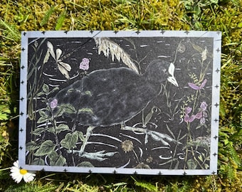 May include: Rectangular art print featuring a black bird in a marsh scene with purple flowers and greenery. The print has a light blue border with star-like designs. A white daisy is in the lower left corner, set against a backdrop of green moss.
