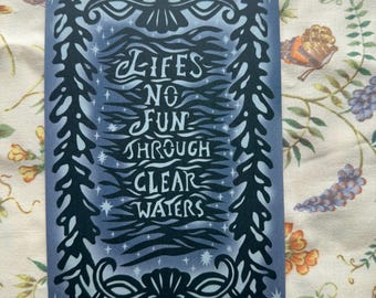 May include: A rectangular card with a blue background and white text that reads "LIFES NO FUN THROUGH CLEAR WATERS." The text is surrounded by a decorative black border with seashell and plant-like designs.