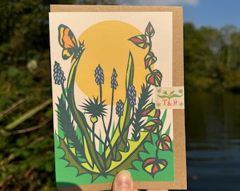 May include: A greeting card with a colorful illustration of a butterfly, flowers, and a sun. The card is on a brown background and has the text "T & H" in the corner.