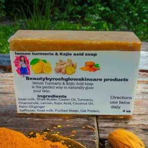 Peut inclure: Une barre de savon jaune avec une étiquette blanche qui indique "lemon turmerio & Kojio aoid soap" et "Beautybyrochglowskincare products". L'étiquette liste également les ingrédients et les instructions d'utilisation. Le savon est posé sur une surface en bois avec un tas de poudre jaune et une amande au premier plan.