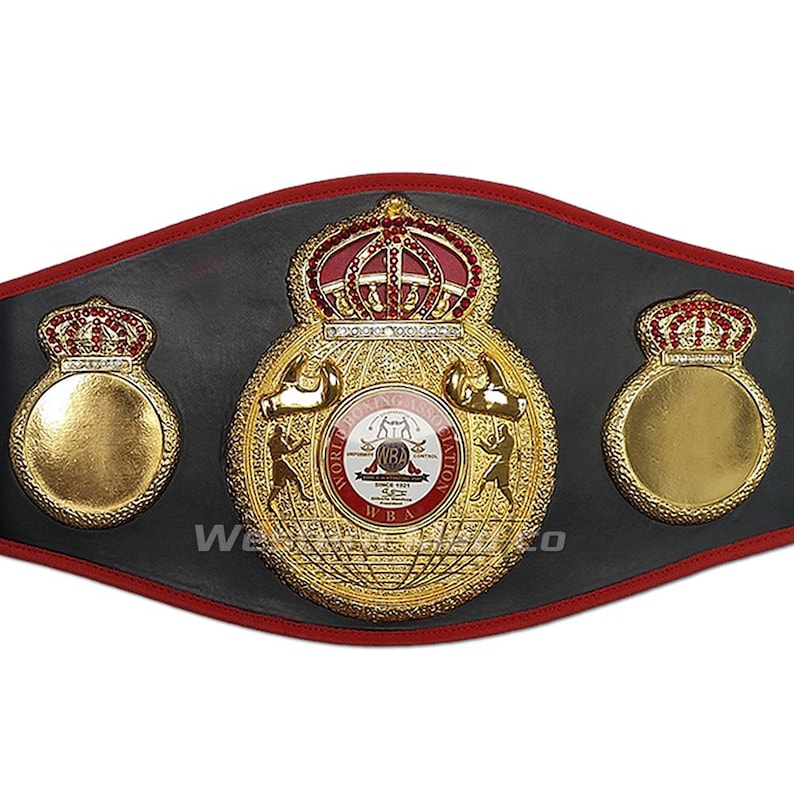 May include: A gold and black boxing championship belt with the words "World Boxing Association" and "WBA" on the front. The belt has two gold crowns on the sides and a larger gold crown on the front.