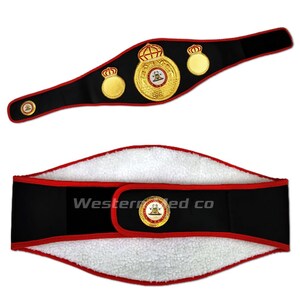 May include: A black boxing championship belt with gold accents and a large central emblem featuring a crown and the words "World Boxing Council". The belt is shown in two positions, one with the buckle facing the viewer and the other with the inside of the belt facing the viewer.