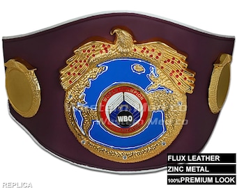 May include: A replica WBO World Boxing Organisation title belt with a burgundy leather strap, gold accents, and a large central emblem featuring a globe with an eagle and the words "World Champion" and "WBO Organization".