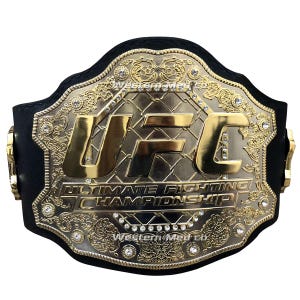 Pu&ograve; includere: Una cintura da campione UFC in oro e argento con cinturini in pelle nera. La cintura presenta un grande logo UFC con strass e le parole "Ultimate Fighting Championship".