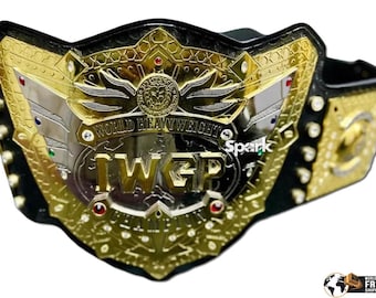 Pode incluir: Um cinturão de campeonato mundial de pesos pesados IWGP em ouro e prata. O cinturão apresenta uma grande placa central com as palavras "WORLD HEAVYWEIGHT" e "IWGP". O cinturão tem uma correia de couro preta e é adornado com pedras preciosas vermelhas e transparentes.
