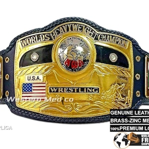 May include: A replica gold and black wrestling championship belt with the words "Worlds Heavyweight Champion" and "Wrestling" on it. The belt has a black leather strap with metal plates and a large center plate with a globe design. The belt is decorated with red, white, and blue accents.
