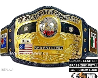 Può includere: Una cintura da campionato di wrestling in oro e nero, replica, con le parole "Worlds Heavyweight Champion" e "Wrestling" su di essa. La cintura ha un cinturino in pelle nera con placche metalliche e una grande placca centrale con un design a globo. La cintura è decorata con accenti rosso, bianco e blu.