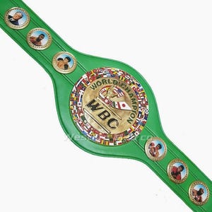 May include: Green leather boxing championship belt with a gold buckle featuring the World Boxing Council (WBC) logo and the words "World Champion". The buckle is surrounded by a circle of flags representing different countries.