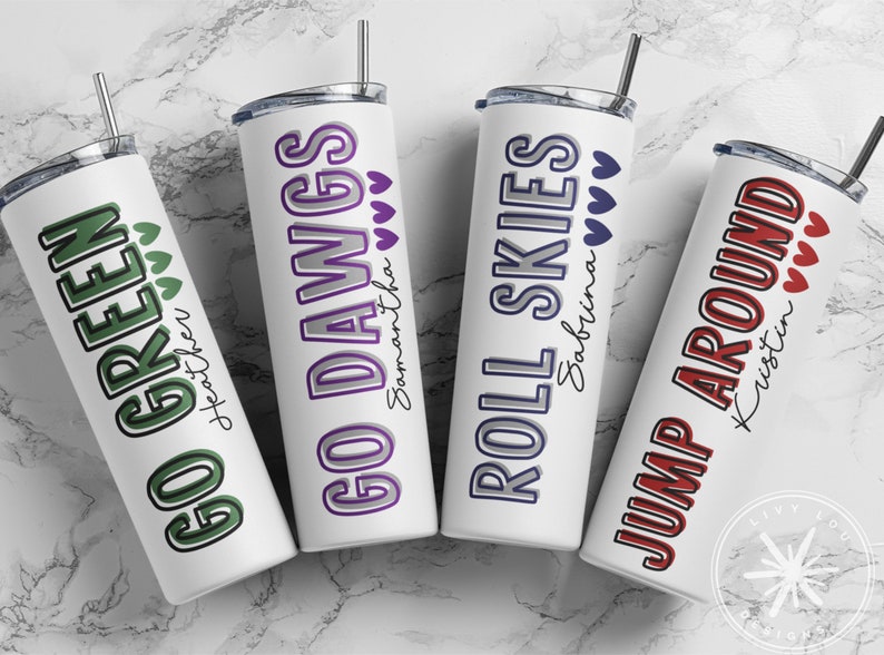 May include: Four white stainless steel tumblers with various phrases and names printed on them. The phrases include "GO GREEN", "GO DAWGS", "ROLL SKIES", and "JUMP AROUND". Each tumbler has a different color scheme and heart accents.