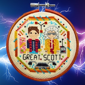 May include: Cross-stitch embroidery in a wooden hoop featuring characters from the movie "Back to the Future." The design includes Marty McFly and Doc Brown, with the phrase "GREAT. SCOTT." The artwork is surrounded by colorful accents and a DeLorean.