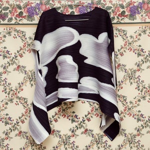May include: A black and white pleated top with a cloud-like pattern. The top is made of a lightweight fabric and has a loose, flowing fit.