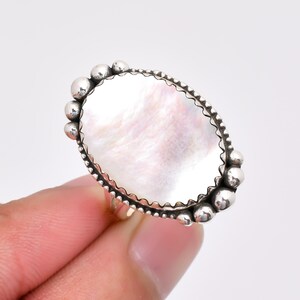 Op de afbeelding: Een zilveren ring met een ovale witte parelmoer steen gezet in een geperlde bezel.
