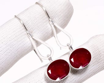 Peut inclure: Paire de boucles d'oreilles pendantes en argent avec des pierres précieuses ovales rouge foncé. Les pierres sont serties dans une lunette en argent, présentées sur fond blanc.
