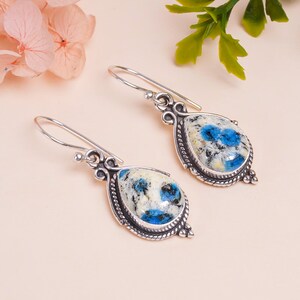 Può includere: Un paio di orecchini pendenti in argento con ciondoli a forma di goccia di pietra blu e bianca.