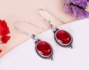 Peut inclure: Une paire de boucles d'oreilles pendantes en argent avec des pierres ovales rouges. Les boucles d'oreilles ont un design délicat et orné.