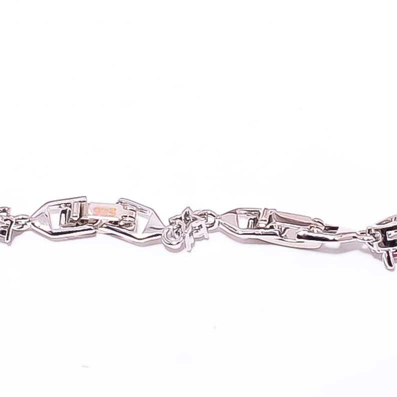 Pode incluir: Um close-up de uma pulseira de corrente prateada com um design de elos &uacute;nico. A pulseira tem um fecho e est&aacute; sobre um fundo branco. Os elos t&ecirc;m uma forma geom&eacute;trica.