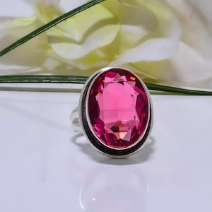 Può includere: Un anello d'argento con una grande pietra preziosa rosa ovale sfaccettata incastonata in una montatura a  bezel.