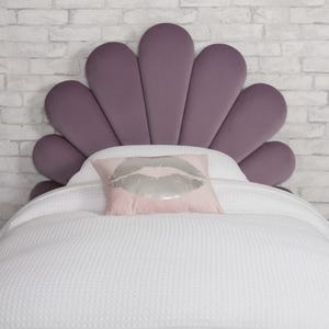 Può includere: Una testiera in velluto viola con un design a forma di ventaglio. Un cuscino rosa con una stampa di labbra argentate poggia su un letto bianco. Il letto è coperto da una coperta bianca a nido d'ape. La testiera è larga circa 152 cm.