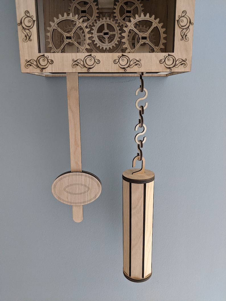 May include: A wooden clock with a pendulum and weights. The clock has a decorative design with gears and scrolls. The pendulum is made of wood and has a round weight at the bottom. The weights are also made of wood and have a cylindrical shape.