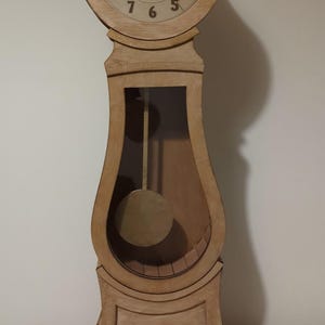 May include: A wooden grandfather clock with a white face and black hands. The clock has a pendulum and a drawer at the bottom.