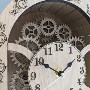 May include: A wooden clock with a circular face and black hands. The clock face has Roman numerals for the hours and Arabic numerals for the minutes. The clock is surrounded by gears, giving it a steampunk aesthetic.