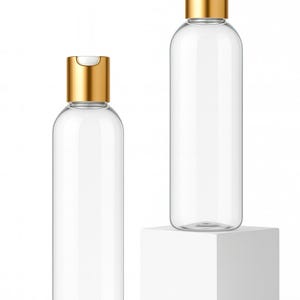 K&ouml;nnte beinhalten: Zwei transparente, zylindrische Flaschen mit goldfarbenen Klappdeckeln. Eine Flasche steht auf einem wei&szlig;en W&uuml;rfel, die andere auf der Oberfl&auml;che. Die Flaschen sind leer und scheinen aus Glas oder klarem Kunststoff zu bestehen.