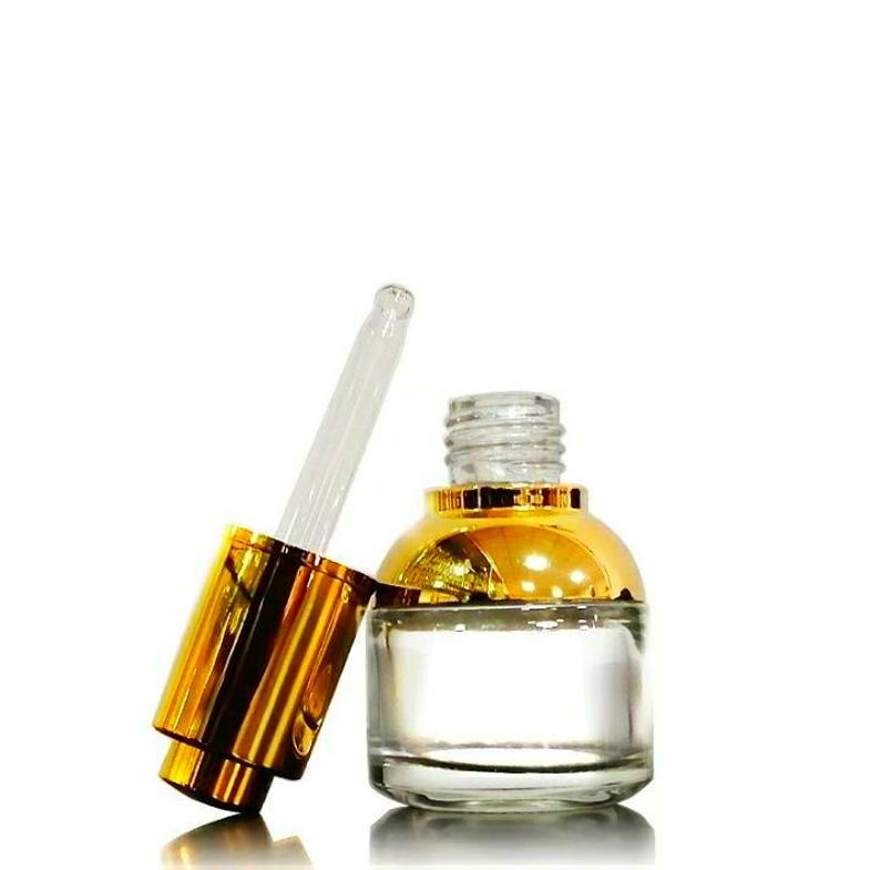 May include: A clear glass bottle with a gold-coloured cap and a glass dropper. The bottle is partially filled with a clear liquid. The cap is off, and the dropper is angled towards the bottle.
