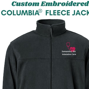 Puede incluir: Chaqueta de forro polar negra Columbia con un estetoscopio y un corazón bordados en rosa. El texto "Samantha, RN Intensive Care" está bordado debajo del diseño.