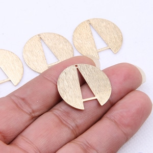 May include: Four gold-colored metal charms in the shape of a circle with a cut-out letter A in the center. The charms have a brushed finish.