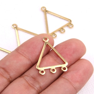 Puede incluir: Pendiente de metal de forma triangular dorada con cuatro anillos de salto en el borde inferior.