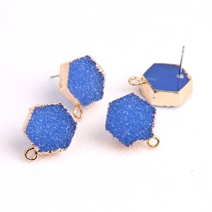 May include: Four blue hexagonal shaped earring charms with gold accents. Two charms have a loop for attaching to a chain or bracelet, and two charms have a post for attaching to an earring.