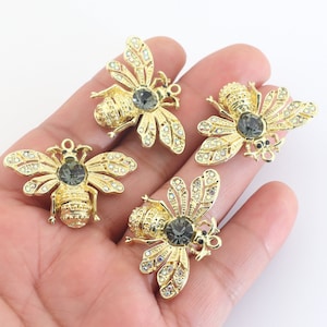 May include: Four gold bee charms with clear rhinestone accents and black crystal centers. The bees are detailed with wings, antennae, and legs.