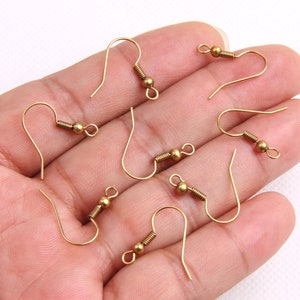 Peut inclure: Un ensemble de dix crochets d'oreille dorés avec une fermeture à ressort. Les crochets sont en métal et ont une finition lisse.