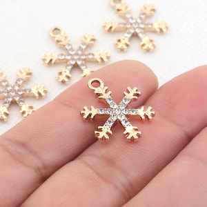 May include: Gold snowflake charms with clear rhinestones. The charms have a loop at the top for attaching to jewelry or other crafts.