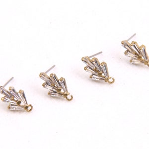 May include: Three gold-tone earring findings with clear crystal accents. Each finding has a small loop at the bottom.