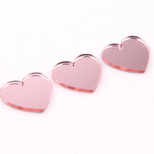 May include: Three pink mirrored heart-shaped acrylic charms.