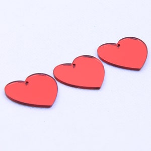 May include: Three red heart-shaped acrylic charms with a hole at the top for hanging.